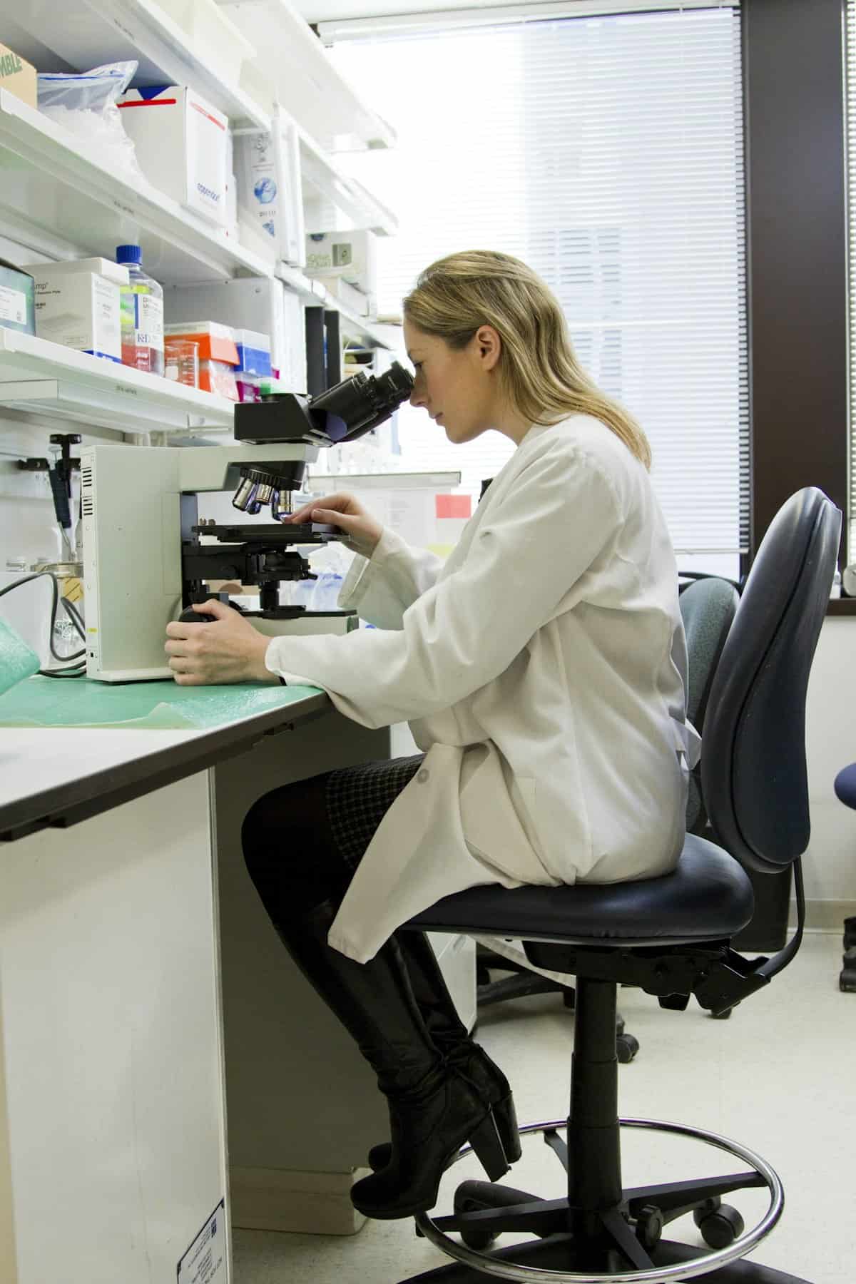 Laboratory workspace with scientific equipment including microscope, glass slides, and research supplies arranged on clean bench
